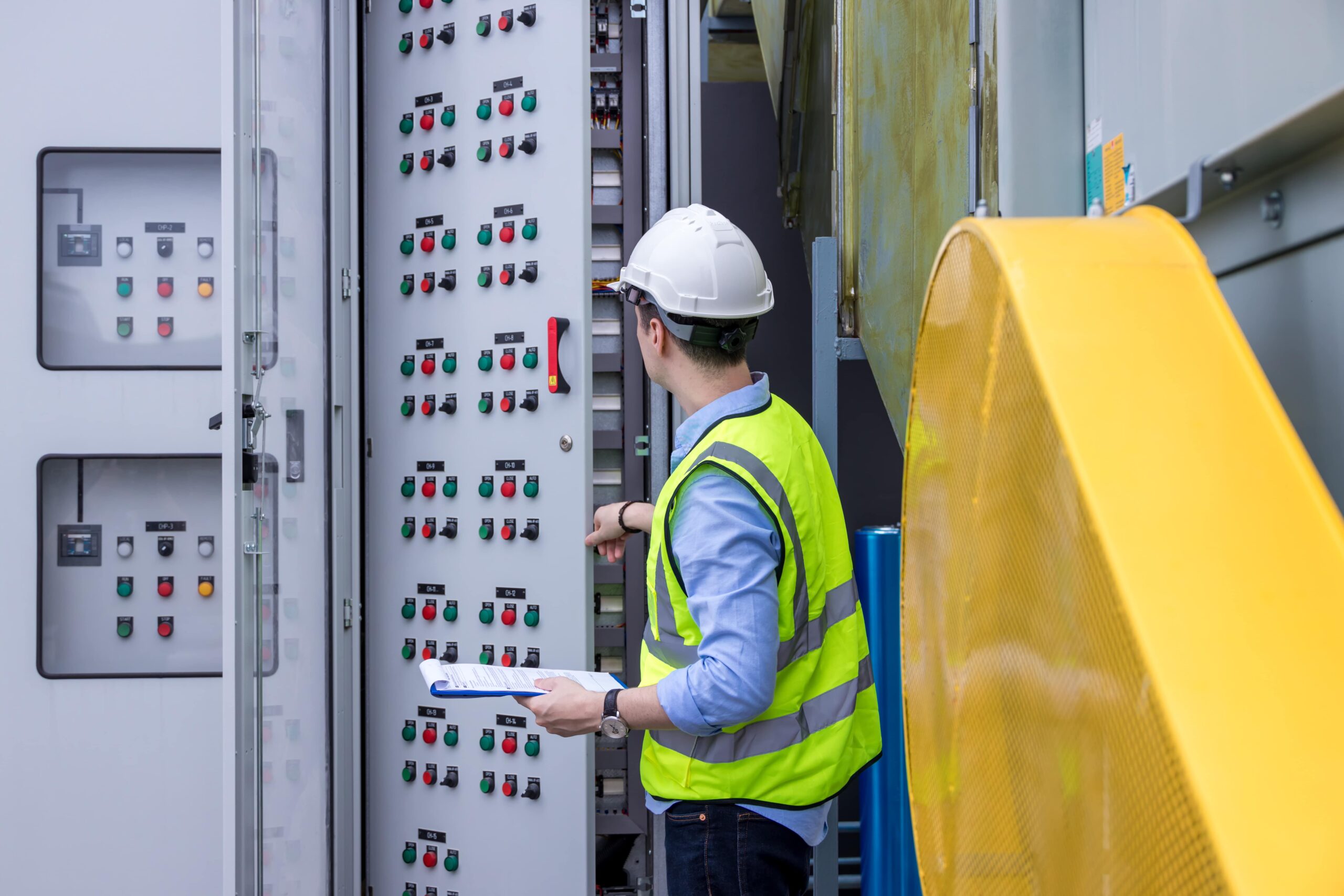 Ingeniero revisando cuadro de control eléctrico industrial durante puesta en servicio