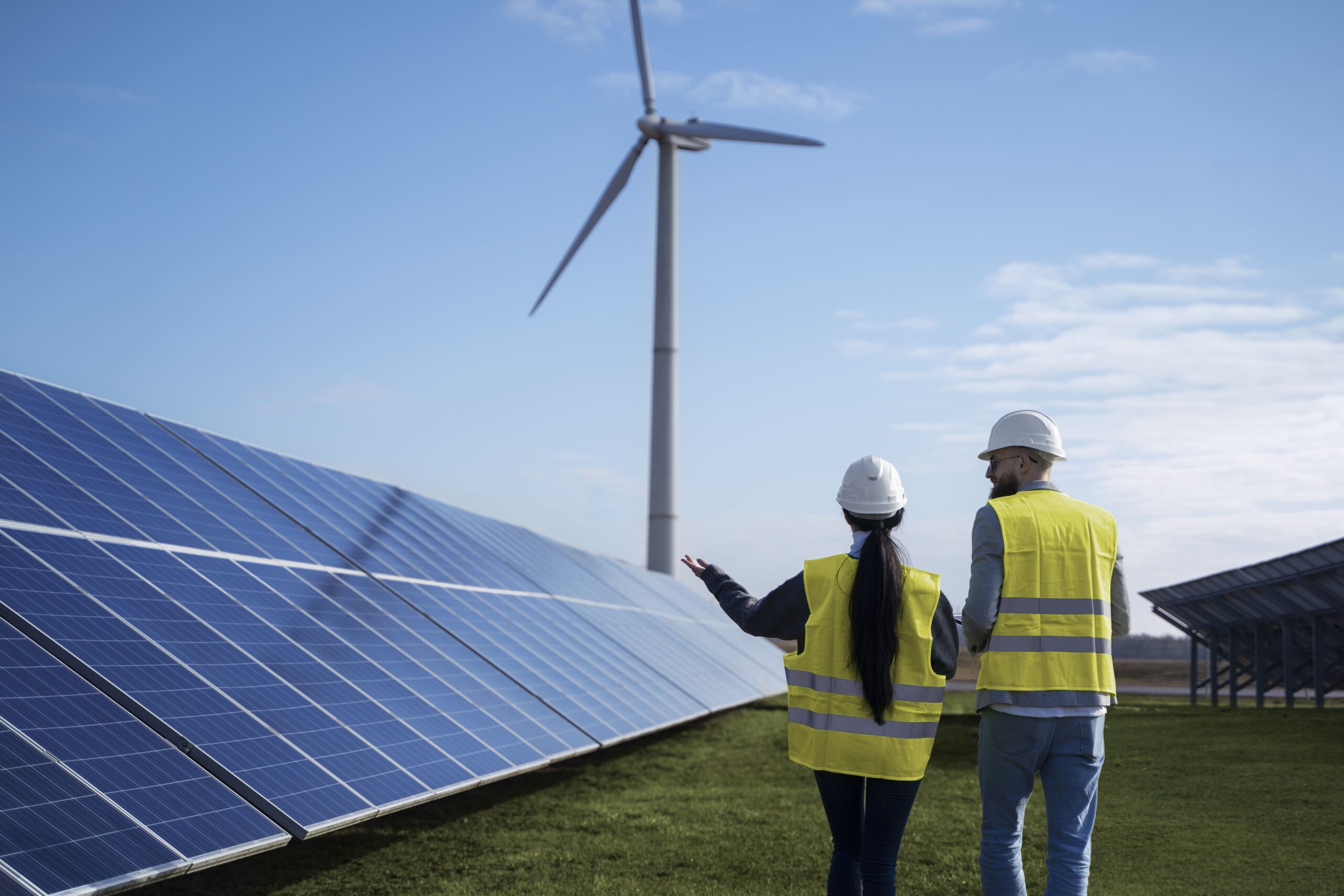 Técnicos supervisando una planta de energía solar y eólica con sistemas digitales de mantenimiento predictivo y monitorización en tiempo real.