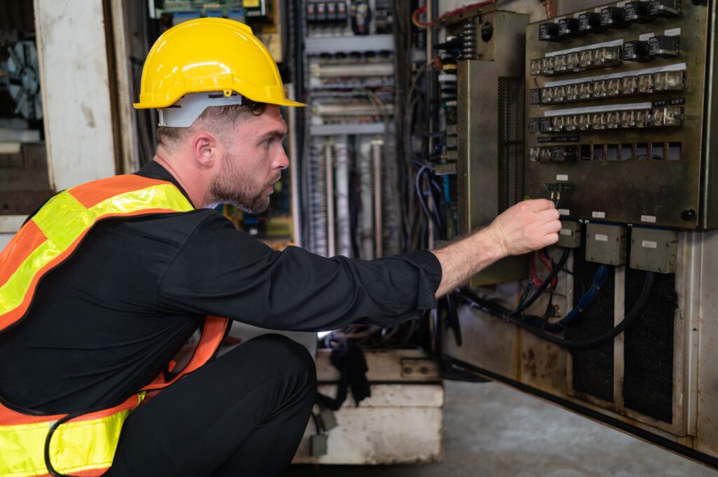 Técnico inspeccionando conexiones en cuadro eléctrico industrial durante mantenimiento correctivo — VOLTIA