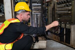 Técnico inspeccionando conexiones en cuadro eléctrico industrial durante mantenimiento correctivo — VOLTIA