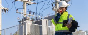 Ingeniero eléctrico con tablet analizando instalación de alta tensión en subestación eléctrica — análisis de redes eléctricas industriales