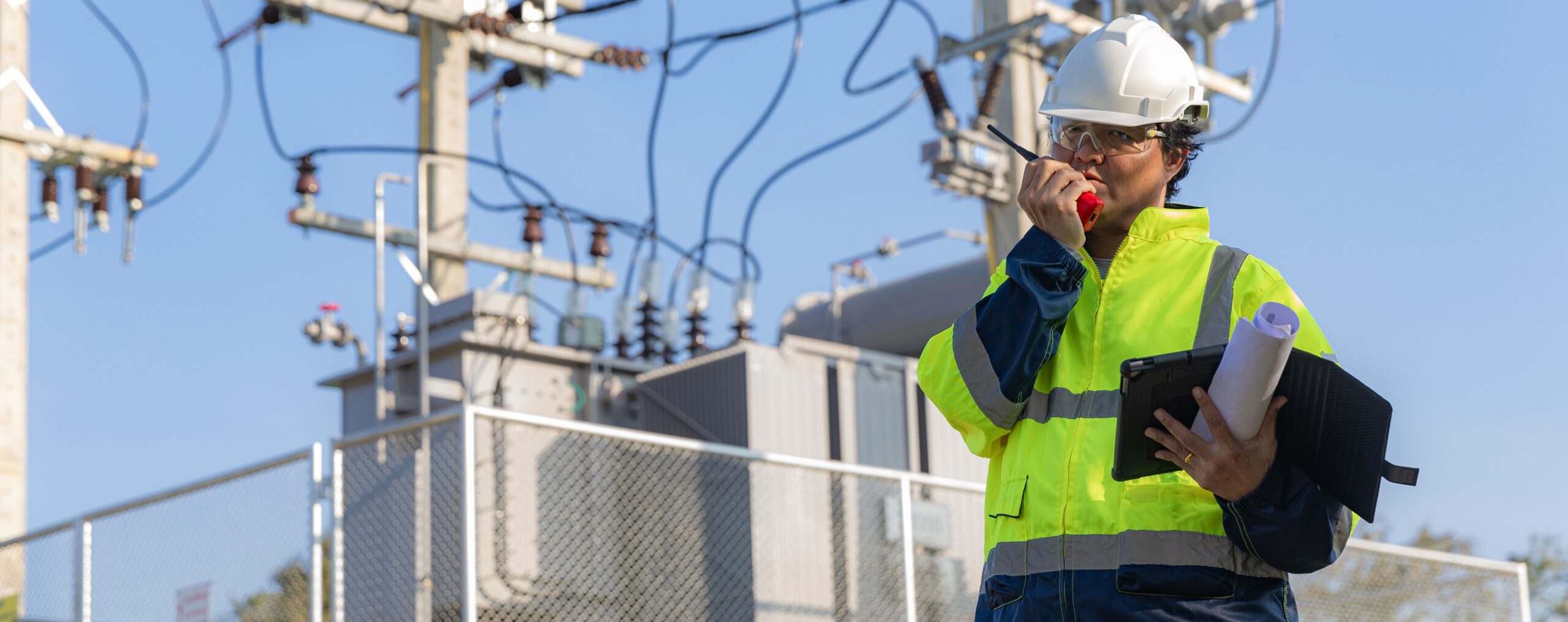 Ingeniero eléctrico con tablet analizando instalación de alta tensión en subestación eléctrica — análisis de redes eléctricas industriales